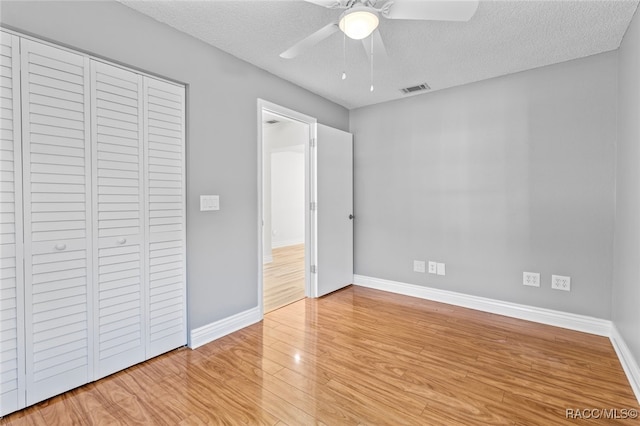 unfurnished bedroom with a closet, ceiling fan, light hardwood / wood-style flooring, and a textured ceiling