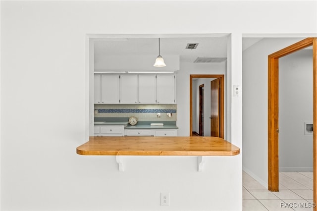 kitchen featuring pendant lighting, wood counters, decorative backsplash, white cabinetry, and a breakfast bar area