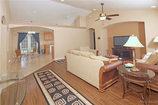 living room featuring ceiling fan with notable chandelier, wood-type flooring, and lofted ceiling