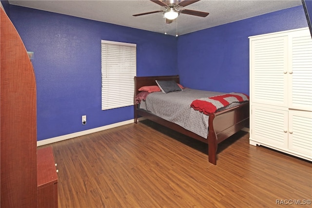 bedroom featuring ceiling fan, dark wood-type flooring, and a textured ceiling