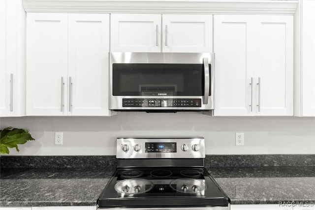 kitchen with white cabinetry, stainless steel appliances, and dark stone counters