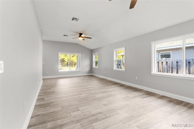 unfurnished room with lofted ceiling, a wealth of natural light, ceiling fan, and light wood-type flooring