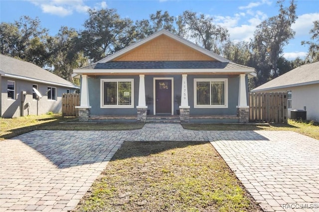 bungalow with a porch, a front yard, and central air condition unit