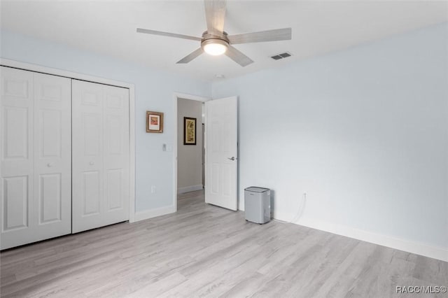 unfurnished bedroom featuring ceiling fan, light hardwood / wood-style floors, and a closet