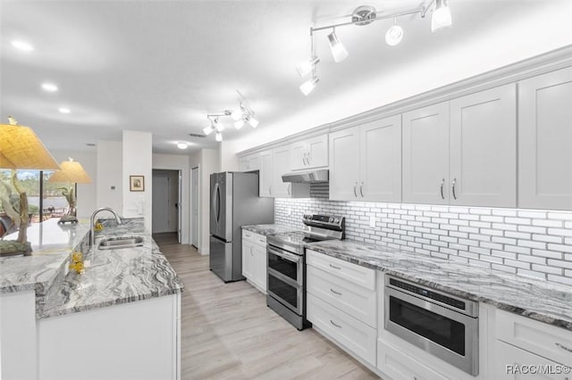 kitchen featuring sink, appliances with stainless steel finishes, backsplash, light stone counters, and white cabinets