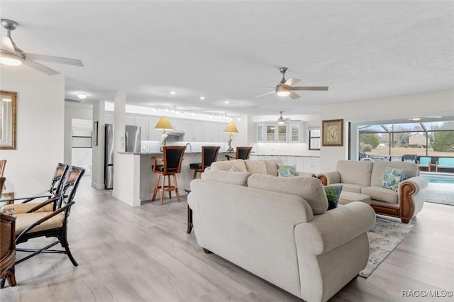 living room featuring ceiling fan and light hardwood / wood-style floors