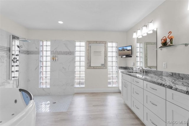 bathroom with a healthy amount of sunlight, vanity, plus walk in shower, and wood-type flooring