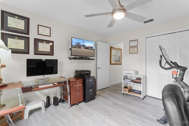 home office with light hardwood / wood-style floors and ceiling fan