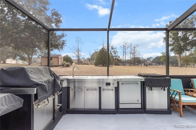 view of patio featuring area for grilling, a storage unit, sink, and glass enclosure