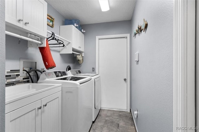 washroom featuring separate washer and dryer, cabinets, and a textured ceiling