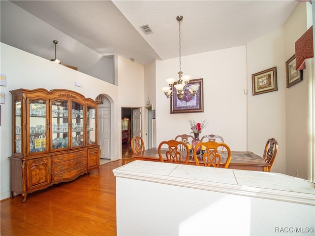 dining area featuring wood-type flooring, lofted ceiling, and a notable chandelier