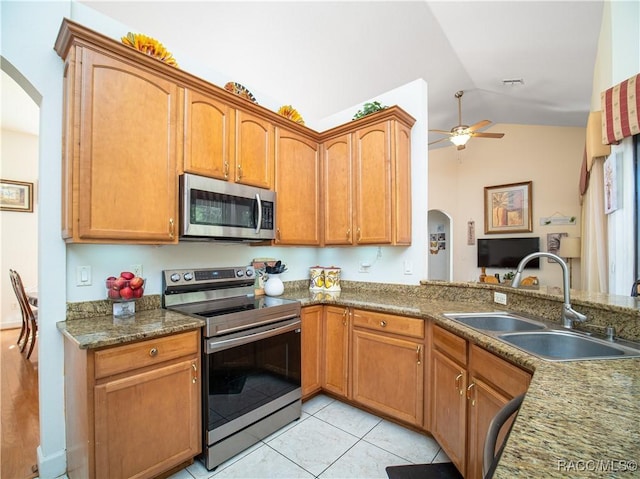 kitchen with ceiling fan, vaulted ceiling, sink, stainless steel appliances, and light tile patterned floors