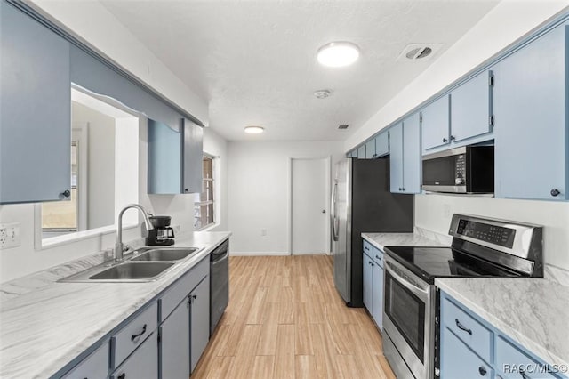 33 New York Blvd, Beverly Hills, FL 34465 - kitchen featuring stainless steel appliances, light countertops, light wood-type flooring, and blue cabinetry