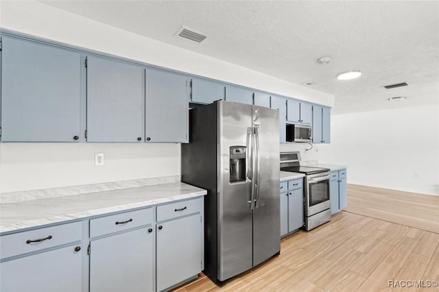 33 New York Blvd, Beverly Hills, FL 34465 - kitchen with appliances with stainless steel finishes, light wood finished floors, and blue cabinets