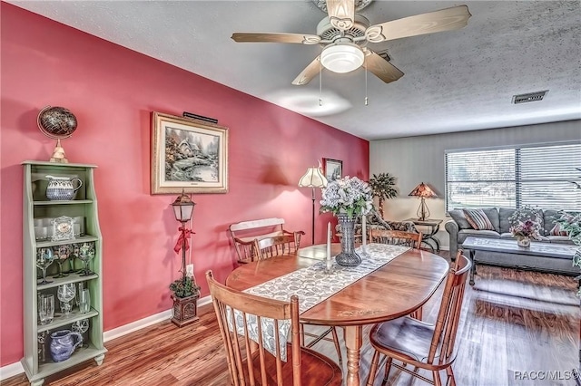 dining room with a textured ceiling, hardwood / wood-style flooring, and ceiling fan