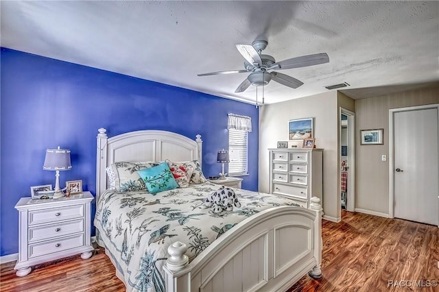 bedroom featuring ceiling fan, hardwood / wood-style floors, and a textured ceiling