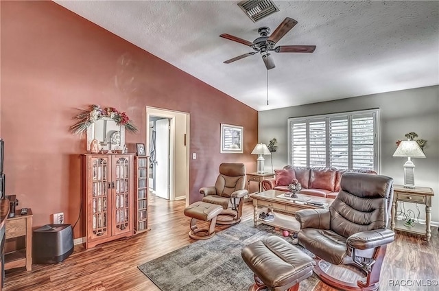 living room with wood-type flooring, a textured ceiling, vaulted ceiling, and ceiling fan