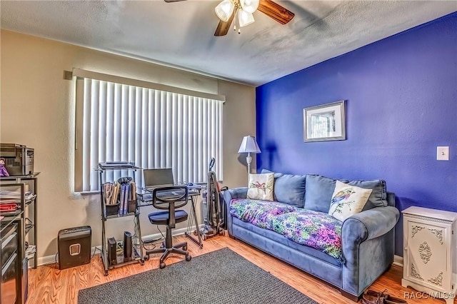 living room featuring wood-type flooring, a textured ceiling, and ceiling fan