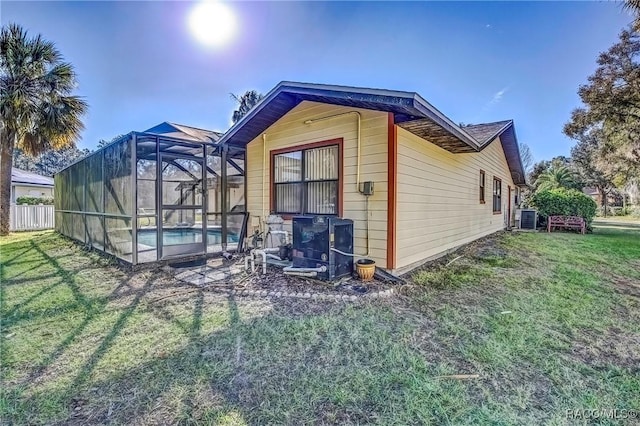 view of side of home with central AC, a yard, and glass enclosure