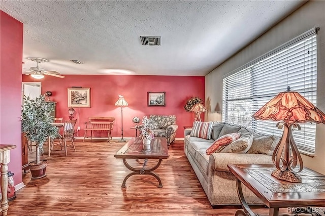 living room featuring hardwood / wood-style floors, a textured ceiling, and ceiling fan