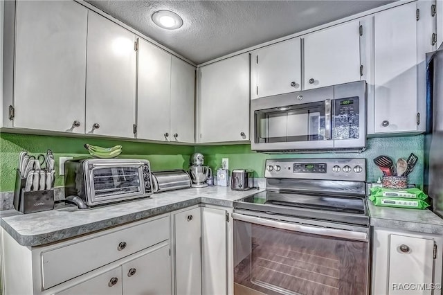 kitchen with white cabinets, a textured ceiling, and appliances with stainless steel finishes