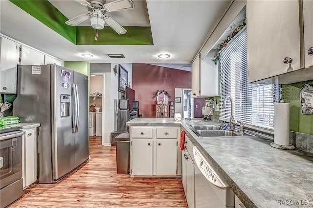 kitchen featuring white cabinets, washing machine and dryer, sink, and stainless steel appliances