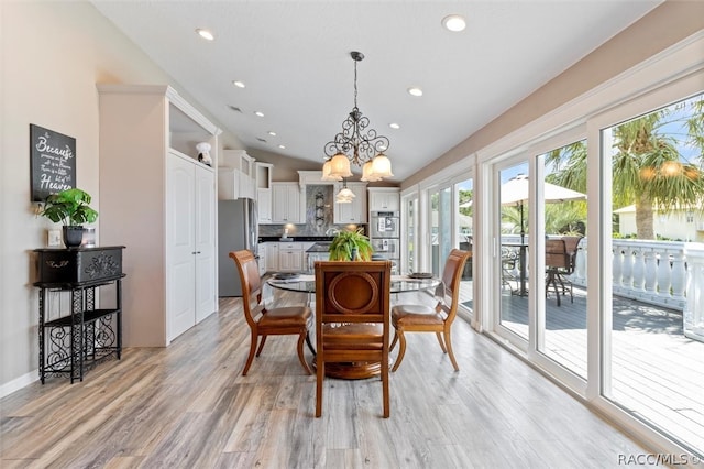 dining room with light hardwood / wood-style floors, lofted ceiling, and an inviting chandelier