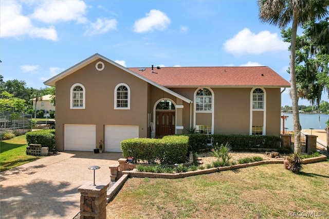 bi-level home featuring a water view, a front lawn, and a garage