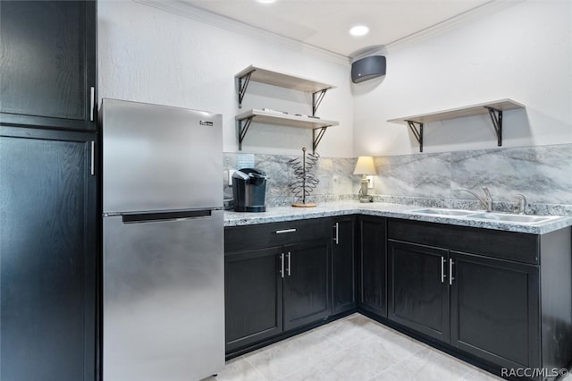 kitchen with stainless steel refrigerator, decorative backsplash, sink, and ornamental molding