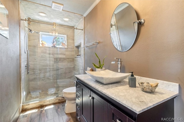 bathroom with vanity, hardwood / wood-style flooring, toilet, ornamental molding, and a shower with shower door