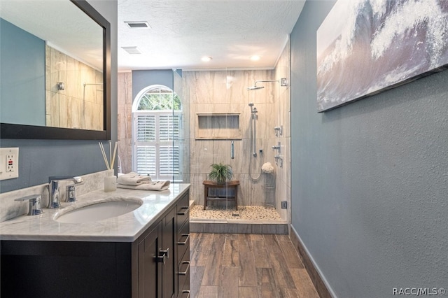 bathroom featuring hardwood / wood-style floors, vanity, a shower with door, and a textured ceiling