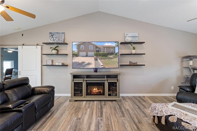 living room featuring wood-type flooring, a barn door, ceiling fan, and lofted ceiling