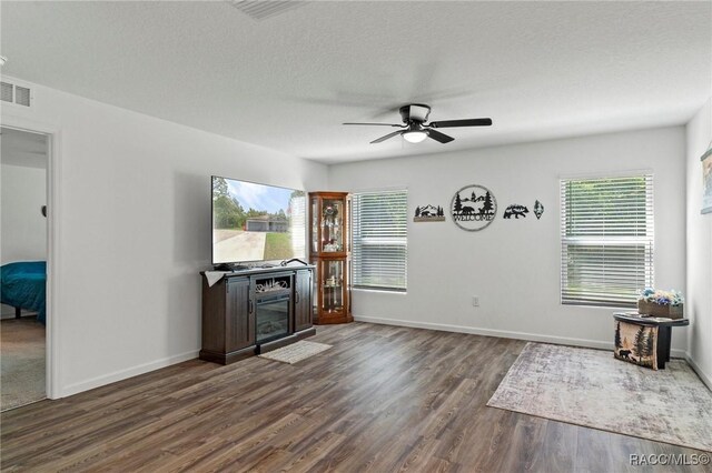 3192 W Barberton Pl, Citrus Springs, FL 34434 - unfurnished living room featuring dark wood finished floors, a ceiling fan, a glass covered fireplace, and baseboards