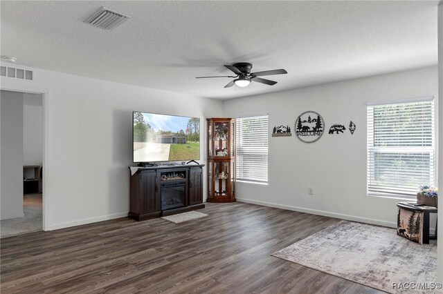 3192 W Barberton Pl, Citrus Springs, FL 34434 - unfurnished living room with a ceiling fan, dark wood-type flooring, baseboards, a fireplace, and a textured ceiling