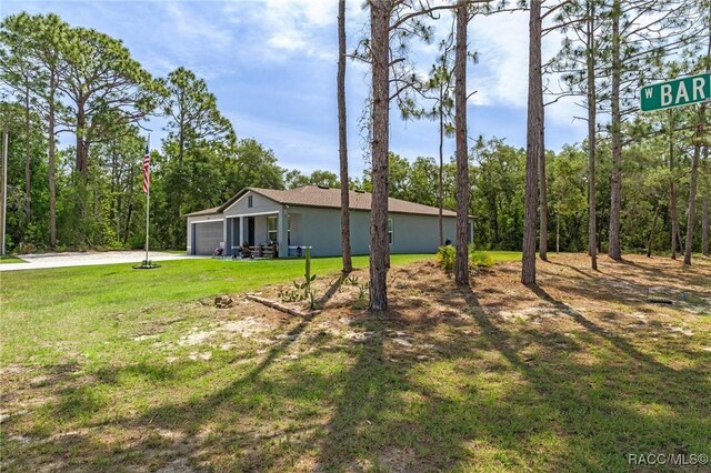 3192 W Barberton Pl, Citrus Springs, FL 34434 - view of side of home featuring an attached garage, a yard, driveway, and an outbuilding
