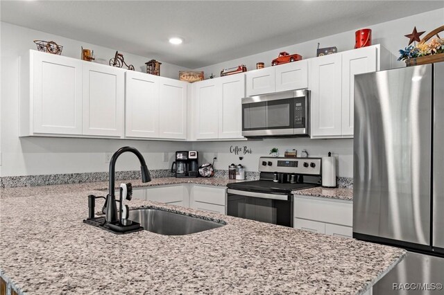 3192 W Barberton Pl, Citrus Springs, FL 34434 - kitchen with stainless steel appliances, a sink, white cabinetry, recessed lighting, and light stone countertops