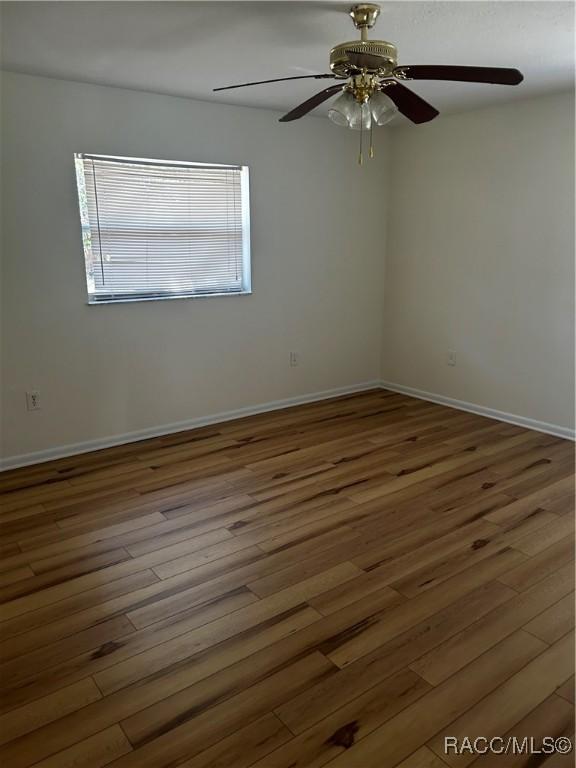 empty room featuring a ceiling fan, wood finished floors, and baseboards