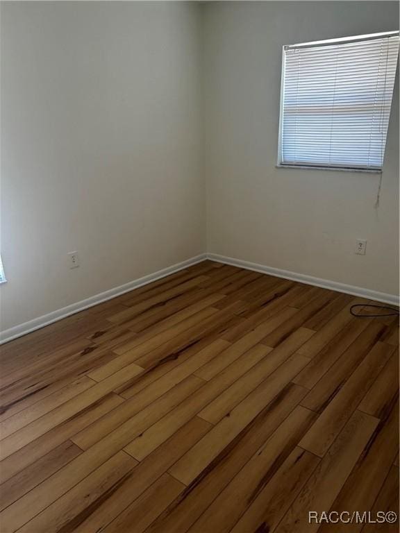 unfurnished room featuring baseboards and wood finished floors