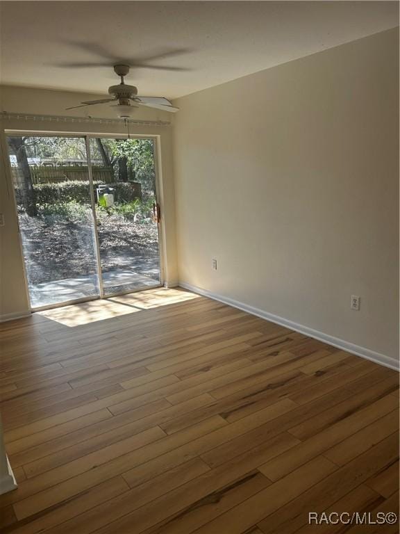 unfurnished room with a ceiling fan, wood finished floors, and baseboards