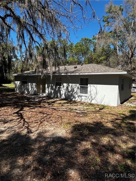 back of property featuring stucco siding and roof with shingles