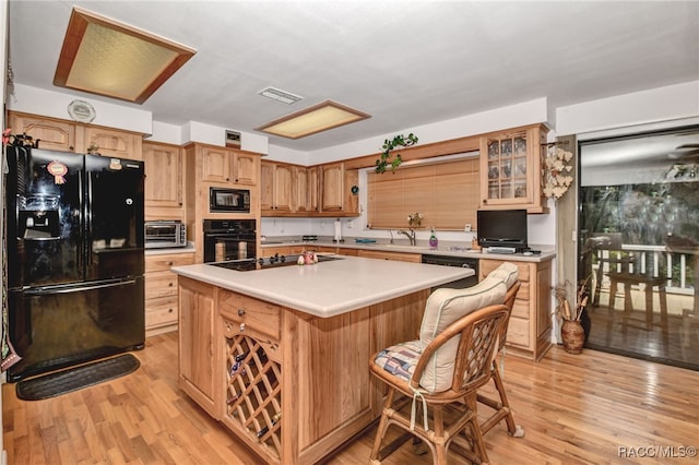 kitchen featuring visible vents, a kitchen island, light wood finished floors, and black appliances