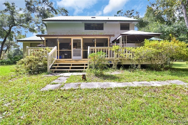 back of house with metal roof and a lawn