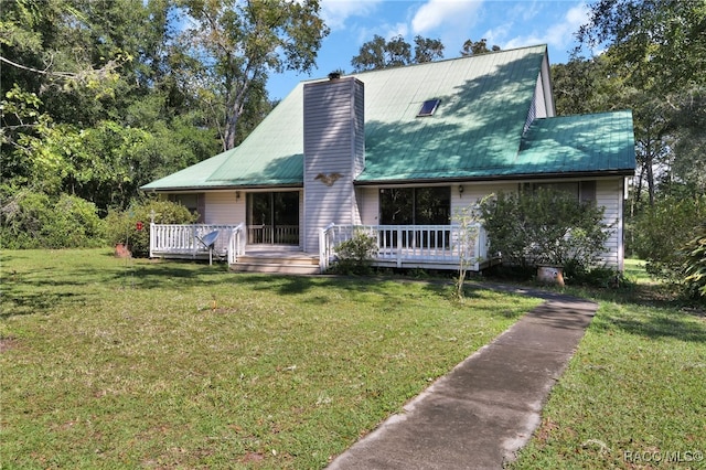 view of front facade with metal roof, a chimney, a front lawn, and a wooden deck