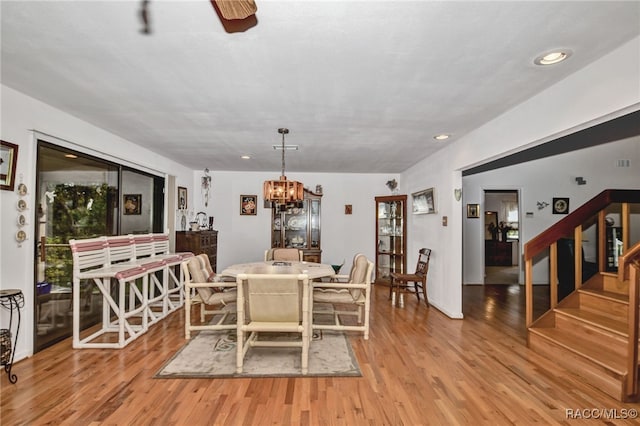 dining room featuring light wood-type flooring, an inviting chandelier, stairs, and recessed lighting