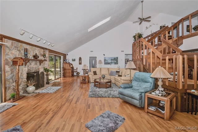 living room featuring a fireplace, stairway, a ceiling fan, wood finished floors, and high vaulted ceiling