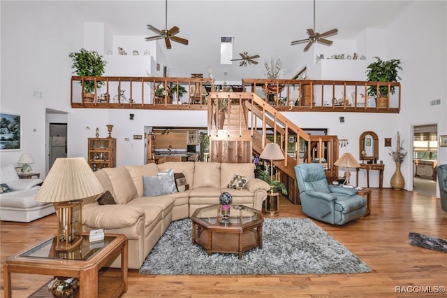 living area with a ceiling fan, wood finished floors, and stairs