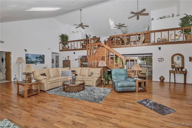 living room featuring high vaulted ceiling, wood finished floors, visible vents, a ceiling fan, and stairway