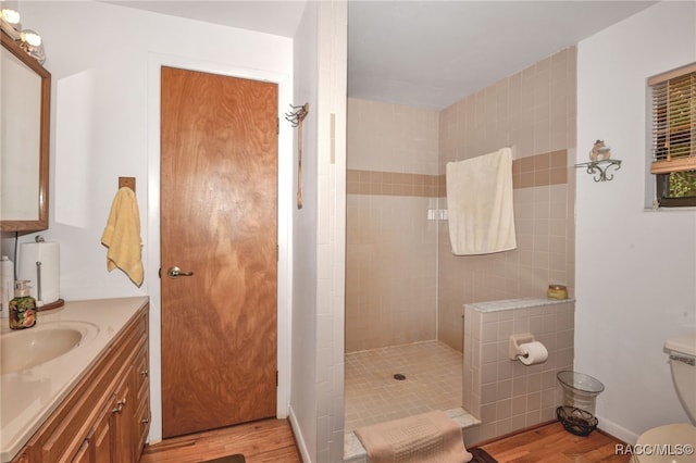 bathroom with a walk in shower, vanity, toilet, and wood finished floors