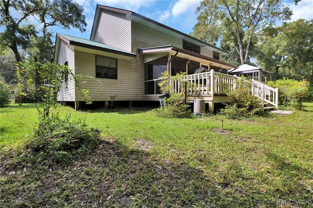 rear view of house with metal roof, a yard, and a deck