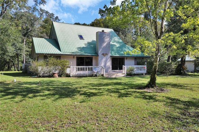 view of front of property with metal roof, a front lawn, a chimney, and a wooden deck